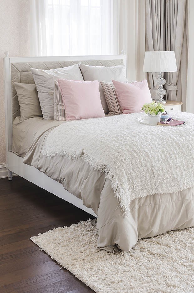 pink pillows on bed with white tray of flower
