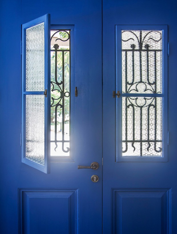 ประตูสีน้ำเงินเข้มติดเหล็กดัดเจาะรูช่องแสงบานประตูเปิดออกได้